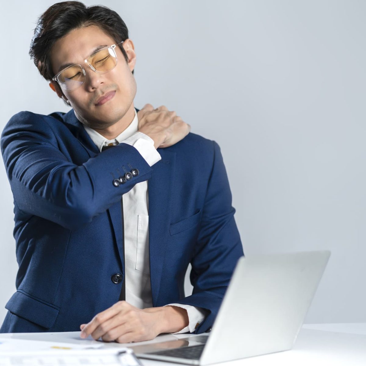 一名商業男性在工作時肩膀感到痛楚